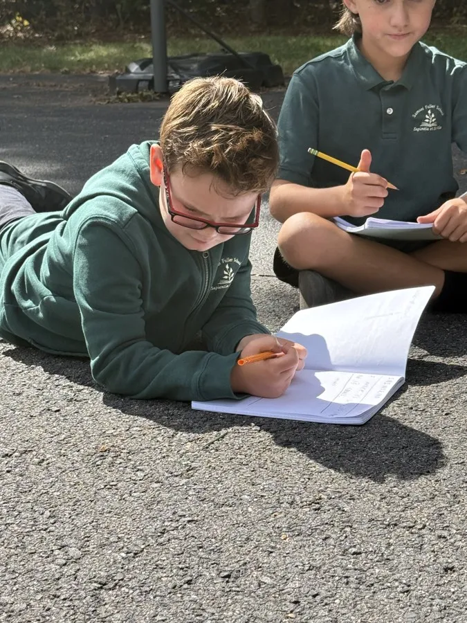 Students writing outdoors on a sunny day